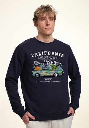 Námořnický modrý svetr s grafikou náklaďáku zdobeného graffiti a textem "CALIFORNIA HIGHWAY ROUTE 1 LOS ANGELES." Měkká látka, kulatý výstřih.