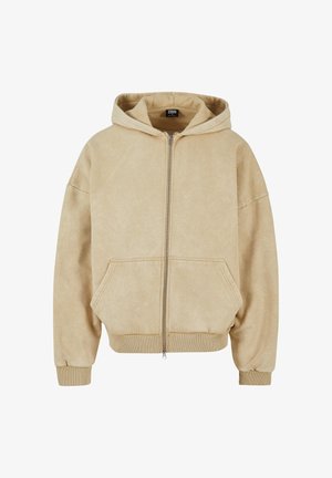 Beige hettegenser med glidelås laget av mykt stoff, med en stor hette, to frontlommer og ribbestrikkede mansjetter og kant. Glatt tekstur og avslappet passform.