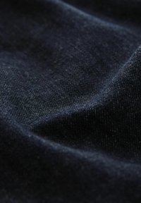 Tamno plava tkanina s teksturiranom površinom, koja ima glatki izgled sličan denimu i suptilni sjaj od različitih debljina niti.