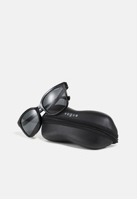 Ochelari de soare negri cu lentile întunecate, având o formă ascuțită și unghiulară. Vine cu un toc protector elegant, de culoare neagră, cu închidere tip zip.