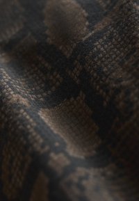 Close-up van een donker stof met een gestructureerd geruit patroon in tinten bruin en zwart.
