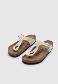 Sandali gialli con zeppa in sughero e suola in gomma nera. Caratterizzati da una cinghia con chiusura e una decorazione a pulsante.