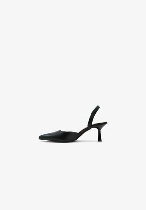 Chaussure slingback noire à bout pointu avec un petit talon évasé contre un fond blanc.