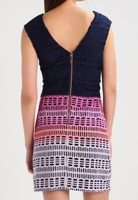 Navy blue textured top with V-back, transitioning to a colorful gradient pattern of pink and white, featuring a center back zipper.