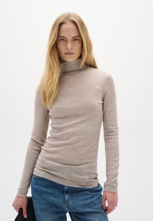 Beige turtleneck sweater with long sleeves, made of a lightweight, textured fabric. Worn with blue denim jeans, featuring a subtle logo detail.