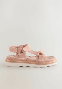 Sandale en daim rose avec des brides réglables, accents de nœud texturé et semelle blanche rembourrée. L'intérieur présente un motif floral.