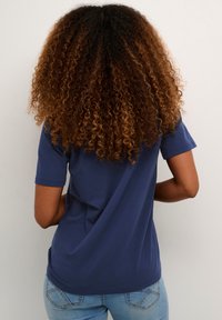 T-shirt a maniche corte di colore blu navy in cotone, vestibilità comoda, con scollo tondo. Visto da dietro con jeans azzurri.