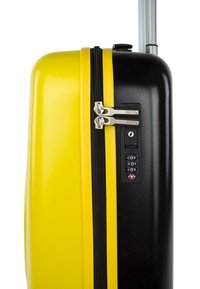 La maleta rígida presenta un diseño amarillo y negro, con cremalleras dobles, cerradura de combinación y un mango telescópico para un transporte fácil.