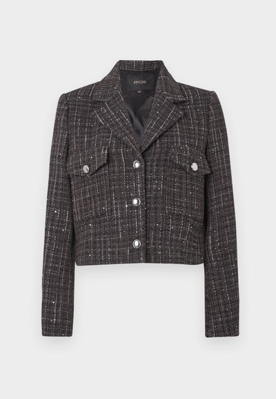 Lühendatud jakk tumedas tviidis ruudulise mustriga, hõbedaste nuppude, kahe ees tasku ja sisselõigetega kraega. Voodriga sisemus.