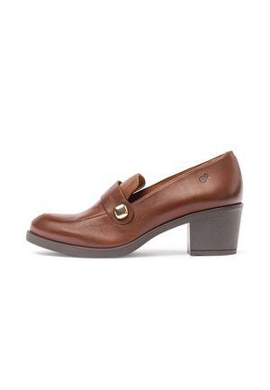 Mocasines de cuero marrón con tacón, con puntera redondeada, que cuentan con una correa decorativa y herrajes en tono plateado. Taco grueso gris. Textura suave.