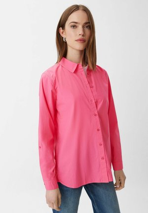 Rosa Langarmhemd mit Kragen, verfügt über eine glatte Textur und abgerundeten Saum, getragen über blauen Jeans.