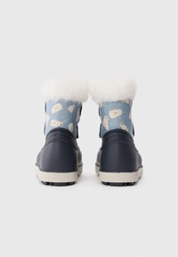 Botas de invierno para niños en color azul marino con ribete de piel blanca y parte superior de tela azul claro con patrones de oso polar y copos de nieve, vistas desde la parte trasera.