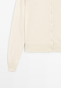 Cardigan couleur crème avec un tricot doux et texturé, doté d'un col rond, de manches longues et de six boutons assortis sur le devant.