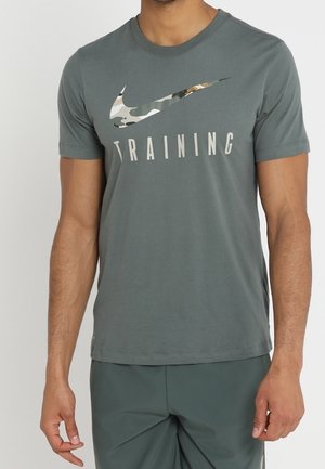Homme portant un t-shirt d'entraînement Nike gris foncé avec un logo Swoosh à motif camouflage et un short gris foncé assorti.