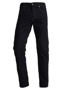 Tmavě modré slim-fit džíny s pěti kapsami a viditelným švem na bílém pozadí.