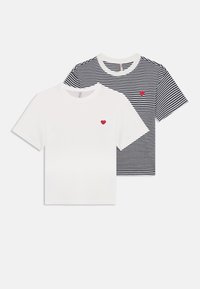 Deux t-shirts : l'un blanc avec un cœur rouge sur la poitrine, et l'autre rayé bleu marine et blanc avec un détail en cœur rouge assorti.
