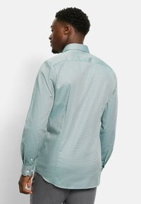 Langärmeliges Hemd in Hellgrün mit einem dezenten Muster, ausgestattet mit einem strukturierten Kragen und geknöpften Manschetten, gefertigt aus glattem Stoff.