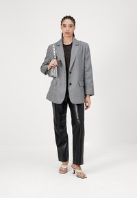 Hall gray suur blazer kahte esipocketiga, kantud musta pitsülikonna peal. Mustad nahkpüksid ja kreemjad kontsakingad täiendavad komplekti.