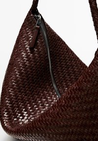 Borsa a mano intrecciata in pelle color bordeaux scuro, con chiusura a zip laterale e superficie liscia e testurizzata dalla forma curva.