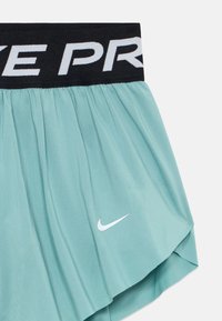 Lys teal atletiske shorts med sort elastisk talje, der har delvis hvid "NIKE PRO" tekst og hvid Nike swoosh logo på benet.