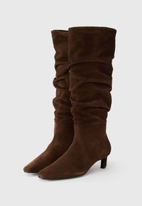 Brown suede knee-high boots with a slouchy design, pointed toe, and low block heel. Features soft texture and gathered fabric at the top.