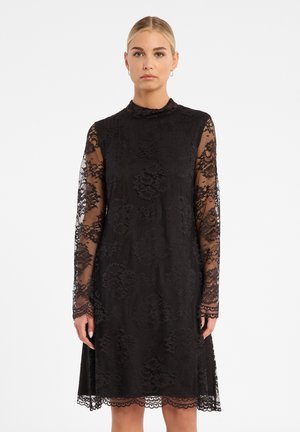 Schwarzes Spitzenkleid mit langen transparenten Ärmeln, hohem Kragen, floralem Muster und gewelltem Saum, das eine figurschmeichelnde Silhouette hat.