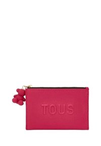 Cartera de cuero rosa con superficie texturizada, que presenta el logo en relieve de "TOUS" y un charm de oso decorativo en color a juego. Cierre de cremallera en la parte superior.