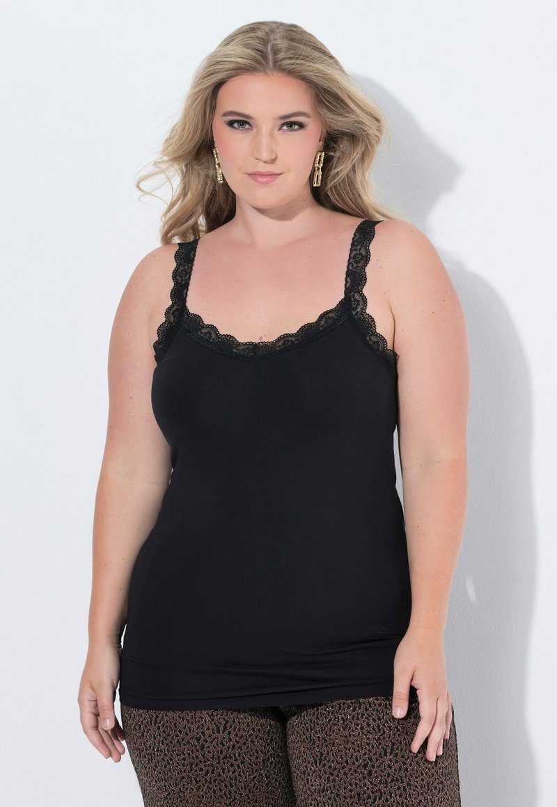 Černý top na ramínka s krajkovými detaily na ramínkách a výstřihu, s uzkým střihem. Nosený s vzorovanými kalhotami.