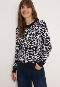 Pull marin avec imprimé léopard blanc, col et ourlet côtelés, encolure ronde, manches longues et texture tricot douce.