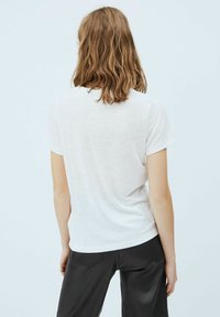 Vit, kortärmad t-shirt i lätt material, med avslappnad passform, rund halsringning och subtil textur.