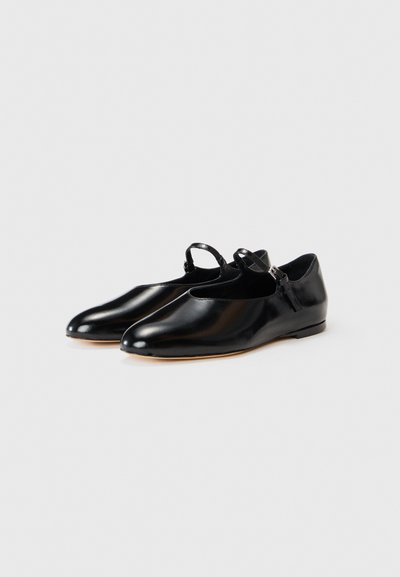 Des chaussures en cuir noir avec une finition brillante, un bout arrondi et une bride à la cheville. Elles présentent un talon bas et une doublure intérieure lisse.