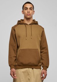 Rudas gobtuvas su kišene priekyje, raišteliu reguliuojamu gobtuvu ir kontrastingos tekstūros skyriais. Pagamintas iš minkštos vidutinio storio medžiagos.