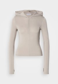 Beige langærmet hoodie med lynlås foran, tætsiddende design og blød tekstur. Har en hætte og tommelfingerhuller på ærmerne.