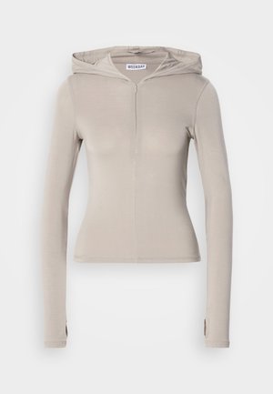 Beige Hoodie mit langen Ärmeln, Frontreißverschluss, taillierter Passform und weicher Textur. Verfügt über eine Kapuze und Daumenlöcher an den Ärmeln.