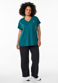 Teal short-sleeve V-neck top paired with black wide-leg pants. Both items feature smooth textures and relaxed fits, with subtle branding.