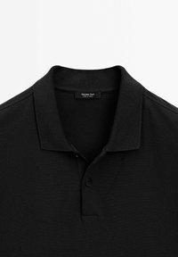 Polo shirt noir à manches courtes avec col et patte de boutonnage à deux boutons, étiqueté Massimo Dutti, posé à plat sur un fond blanc.