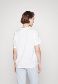 White short-sleeve t-shirt made of cotton, featuring a classic crew neck and a relaxed fit. Visible stitching around the sleeves and hem.
