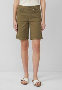 Olijf groene denim shorts met opgerolde boorden, voorzien van een knoopsluiting en zijzakken. Draag het met witte textuur sandalen.