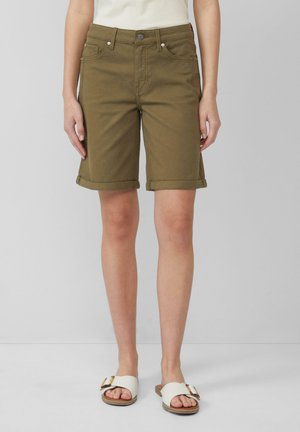 Olivgrüne Denim-Shorts mit umgeschlagenen Säumen, mit Knopfverschluss und Fronttaschen. Getragen mit weißen, strukturierten Sandalen.