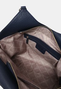 Interno della borsa in pelle blu navy con rivestimento in tessuto beige caratterizzato da un motivo testuale "Liu Jo" e una tasca interna con zip.