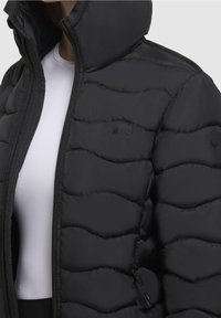 Padded czarna kurtka z wysokim kołnierzem, poziomym wzorem pikowania i zapięciem na zamek. Logo na piersi i gładka faktura materiału.