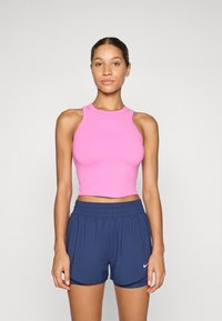Roze getailleerde crop top met een hoge hals en racerback ontwerp, gecombineerd met marineblauwe sportshorts met een elastische tailleband en het Nike-logo.