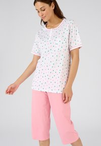 Camiseta de pijama de manga corta de algodón en blanco con un estampado de frutas colorido, combinada con pantalones capri rosas. Cuenta con un bolsillo y ribete en contraste.