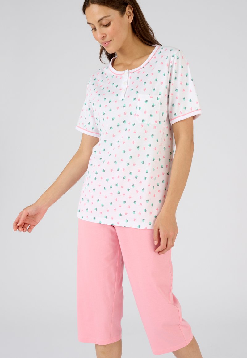 Camiseta de pijama de manga corta de algodón en blanco con un estampado de frutas colorido, combinada con pantalones capri rosas. Cuenta con un bolsillo y ribete en contraste.