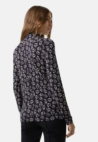 Dlouhý rukáv top s námořnickým pozadím a geometrickým bílým vzorem listů, vyrobený z jemné, hladké tkaniny s přiléhavým střihem.