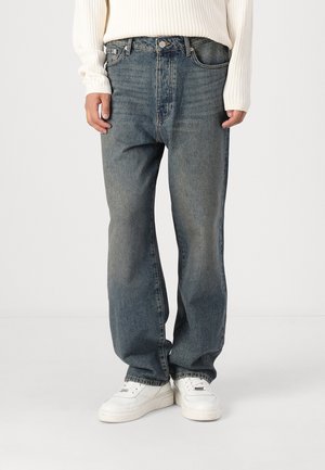 Light blue, faded denim jeans with a straight leg fit. Features a zip fly, belt loops, and five-pocket design. Paired with white sneakers.