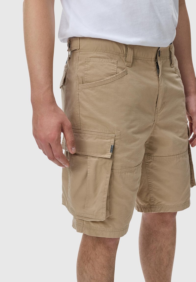 Lys brun cargo shorts med flere lommer, en glatt tekstur og glidelås foran. Har i tillegg en side pocket og forsterkede sømmer.