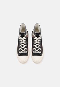 Schwarze High-Top-Sneaker mit weißen Gummisohlen, die weiße Schnürsenkel, kontrastierende Nähte und textile Zungenakzente aufweisen.