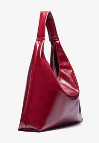 Sac à main en cuir rouge avec une finition brillante, de forme triangulaire et une seule anse large. Présente une large ouverture et un design minimaliste.