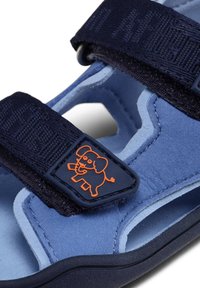 Sandalo blu scamosciato con cinturini blu navy e logo di elefante arancione. Presenta chiusure regolabili con velcro e un design con tagli per la ventilazione.